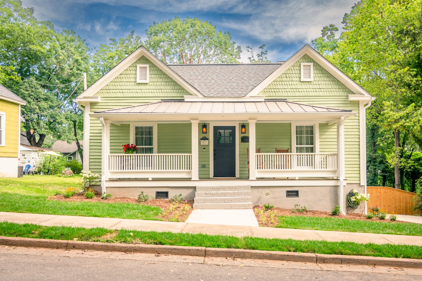 Sebastian House, a green Victorian with twin gables and a welcoming front porch